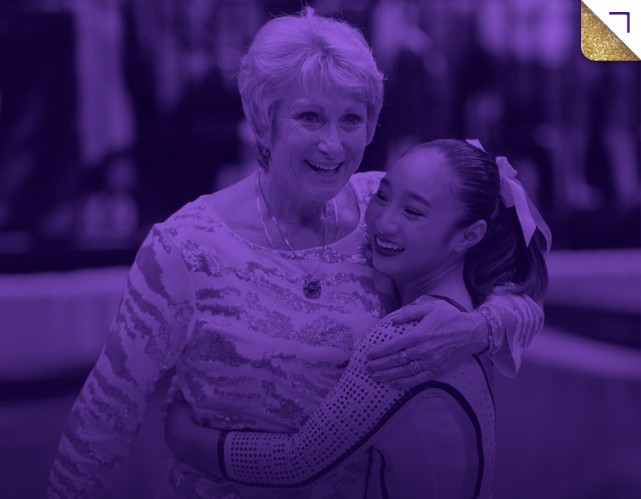 A woman and a young girl are hugging and smiling in a joyful moment, with a blurred crowd in the background.